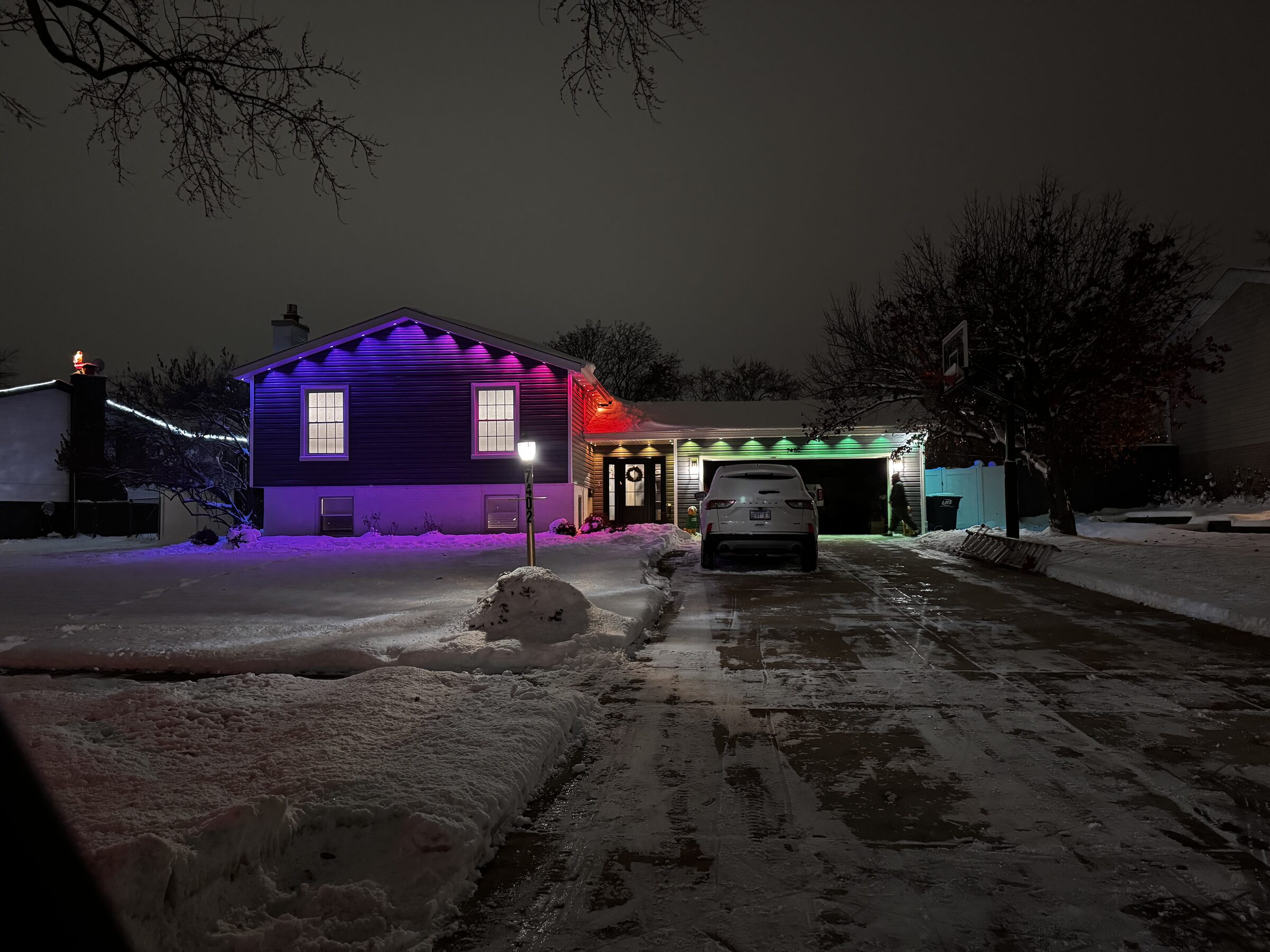Home with permanent color roofline lighting reflecting off fresh snow