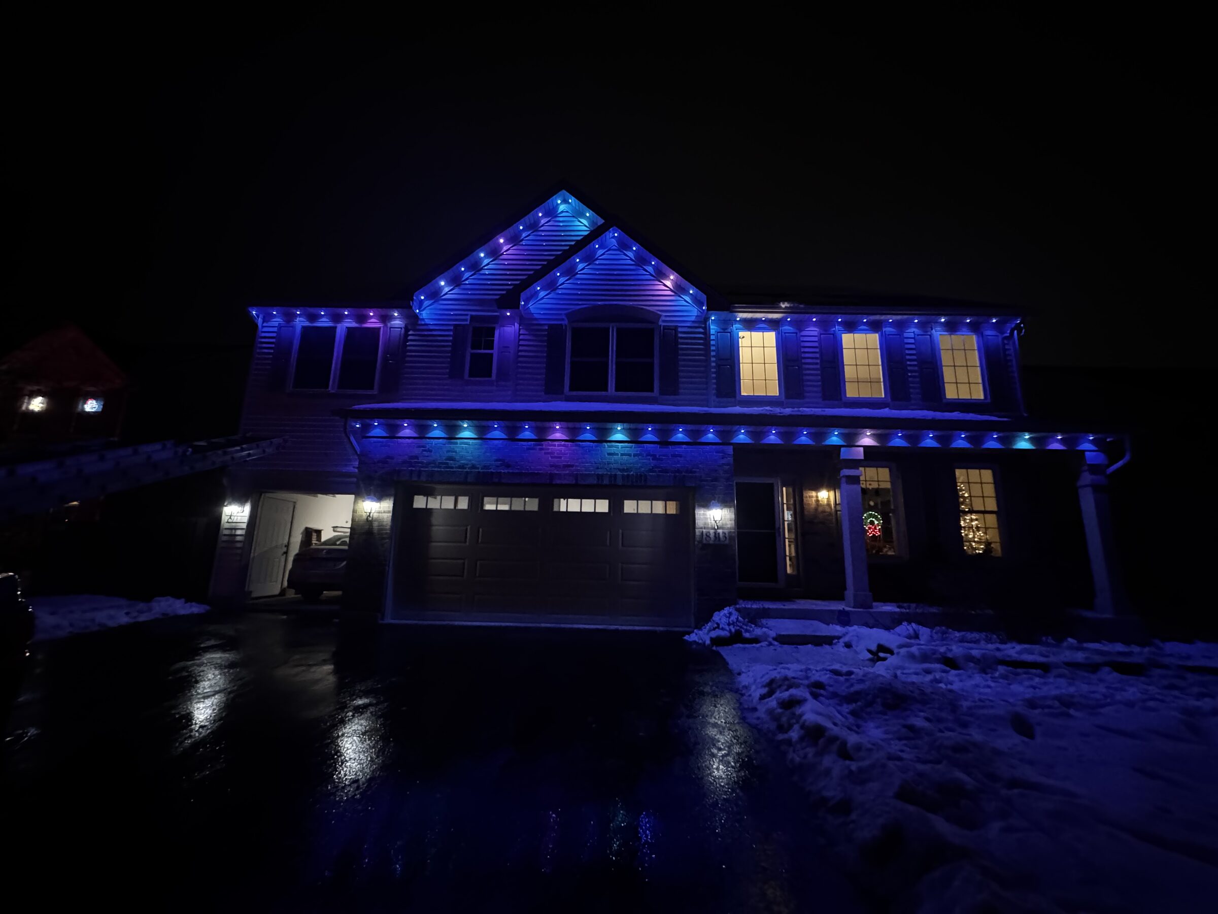 Residential roofline lit in blue by permanent track lighting at night