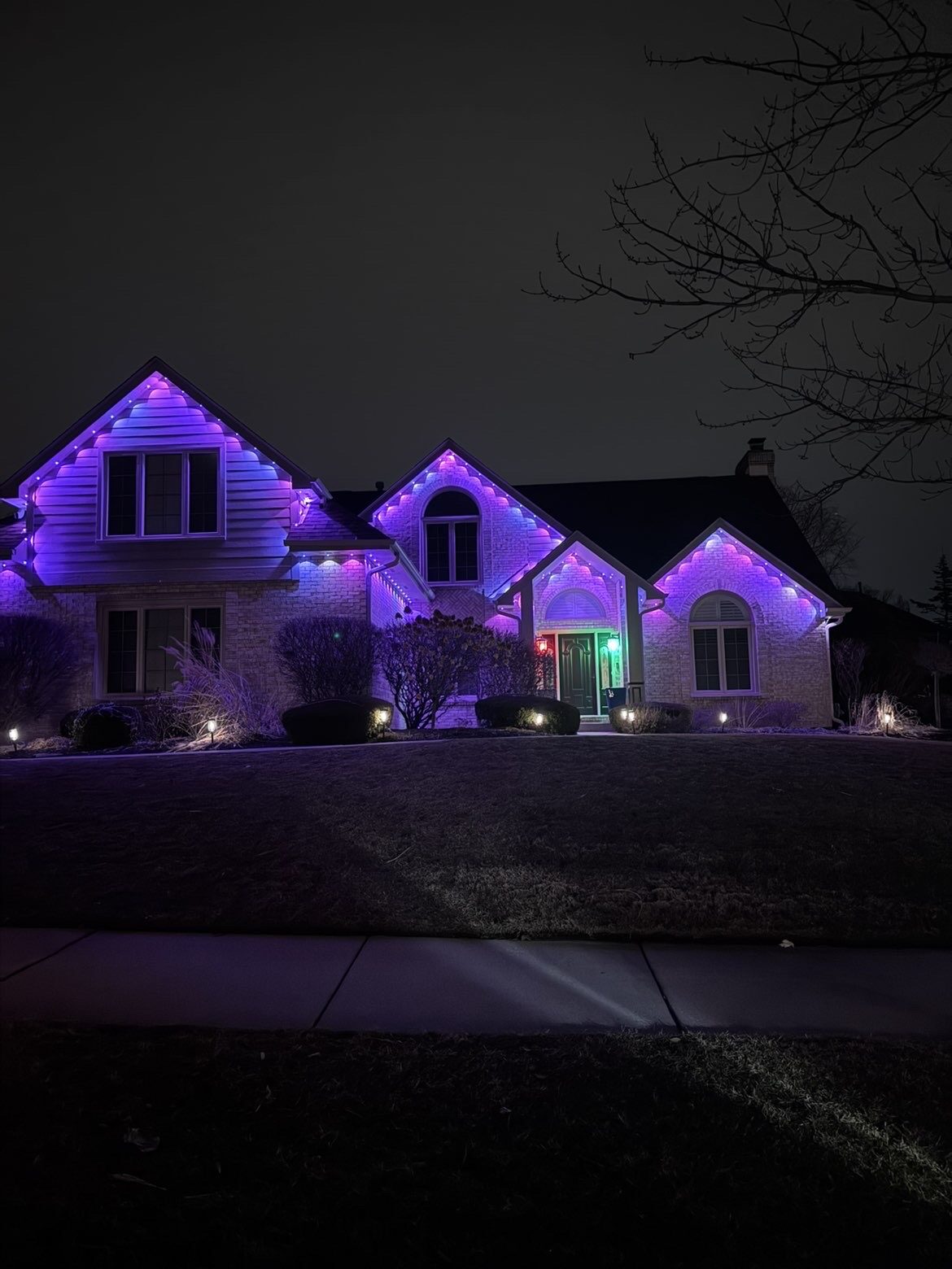 Permanent accent lighting outlining the arches and dormers of a custom home