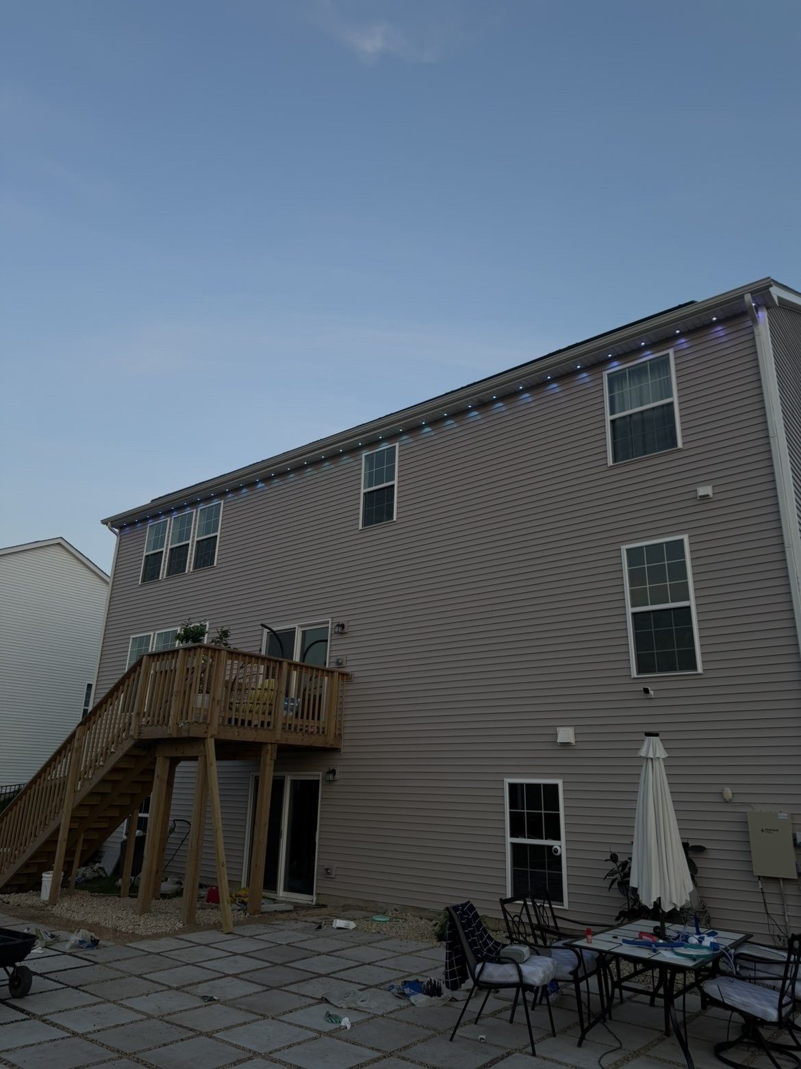 Rear elevation of a home at dusk with permanent lighting installed along the gutter line